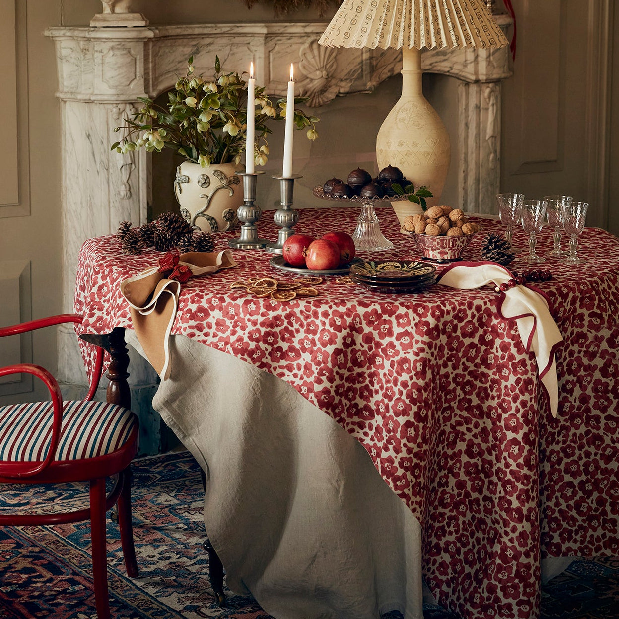 Decorative interior with a table set for a meal, red chair, and wreath on the wall.