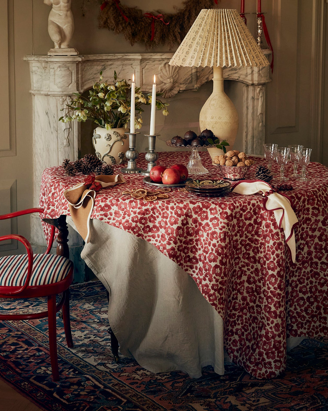 Decorative interior with a table set for a meal, red chair, and wreath on the wall.